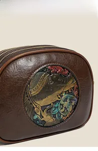 Macro detail of retro leather handbag featuring an embossed elephant totem and gold zippers