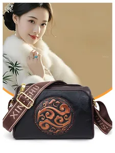 Detail of vintage embossed leather crossbody bag with bronze medallion and woven strap