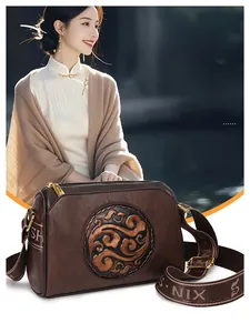 Detail of vintage brown leather handbag with embossed pattern and branded woven strap