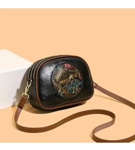 Detail of vintage embossed crossbody bag with bronze elephant relief and ethnic motif