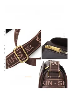 Detailed macro shot of golden metal buckle and jacquard strap on brown leather bag