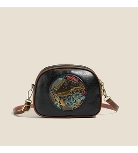 Close-up of retro black crossbody bag with traditional embossed elephant pattern and gold hardware