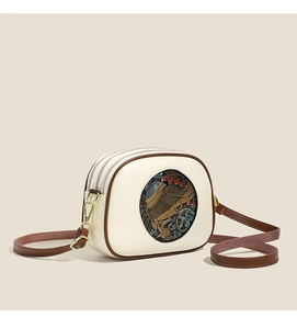 Detail of vintage cream leather shoulder bag featuring intricate circular ethnic embossing