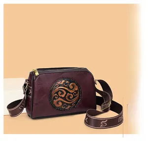 Detailed view of the vintage burgundy crossbody bag with circular embossed floral pattern