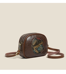 Detail of vintage brown circular crossbody bag with colorful embossed ethnic pattern