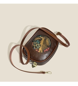 Detailed close-up of brown crossbody bag with embossed elephant and floral patterns