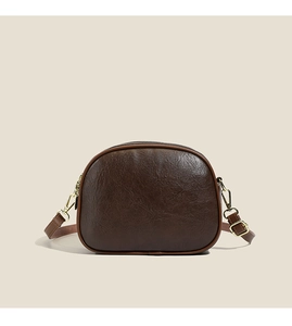Close-up of retro brown crossbody shell bag with textured leather and gold hardware