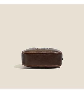 Macro detail of dark brown leather crossbody bag with vintage oil-wax finish and stitching