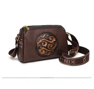 Detail of vintage brown leather crossbody bag with embossed Chinese auspicious cloud pattern