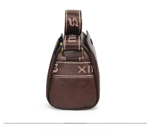 Detailed side view of dark brown embossed leather crossbody bag with wide logo strap