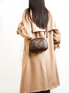 Detail view of a vintage dark brown leather shoulder bag with artistic embossed floral design