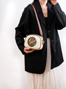Detail of vintage round shoulder bag with embossed elephant pattern on ivory leather