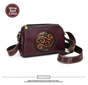 Close-up of wine red vintage embossed leather bag with Chinese pattern and gold zipper