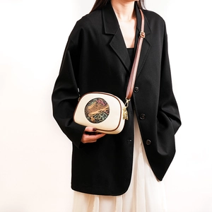 Detail of vintage embossed crossbody bag with elephant pattern embroidery on a female model