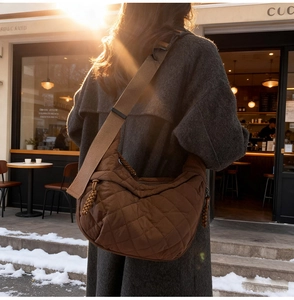 Close-up of brown quilted hobo bag with adjustable strap and textured zipper detail