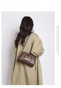 Brown retro crossbody bag featuring embossed cloud patterns on adjustable strap model