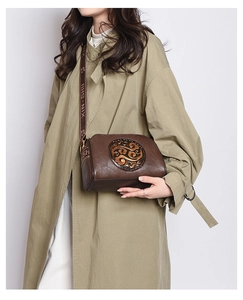 Detailed view of vintage embossed crossbody bag with circular motif and patterned strap