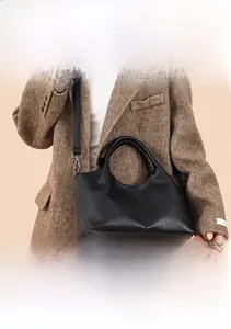 Detailed view of black pebbled leather tote bag with top handles and adjustable strap