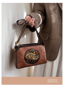 Detail of vintage embossed pattern on brown crossbody bag with decorative strap