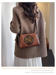 Detail of vintage embossed leather crossbody bag with elegant cloud pattern on brown texture