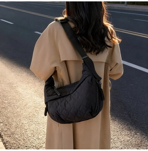 Outdoor lifestyle view of a black quilted crossbody dumpling bag with wide strap