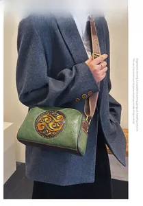 Detail of vintage green pebbled leather crossbody bag with jacquard pattern strap