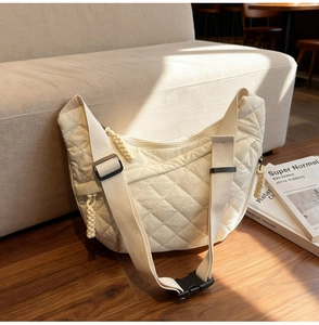 Detail of quilted diamond pattern on cream white hobo bag with woven zipper pull