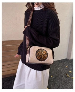 Detail of vintage embossed texture on beige crossbody bag with stylish brown shoulder strap