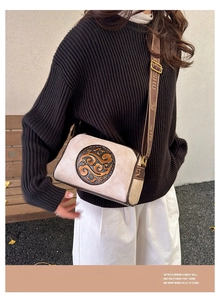 Detail of vintage crossbody bag with traditional Chinese embossed pattern and brown strap