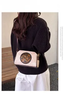 Detail of vintage embossed floral pattern on beige crossbody bag with brown trim