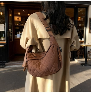 Close-up of brown quilted dumpling bag featuring rhombic texture and woven cord zipper pull