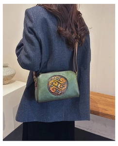 Close-up of vintage embossed leather crossbody bag worn over a grey blazer