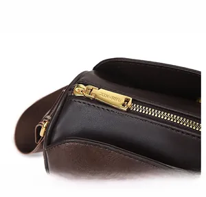 Detailed close-up of golden metal zipper and embossed texture on dark brown leather bag