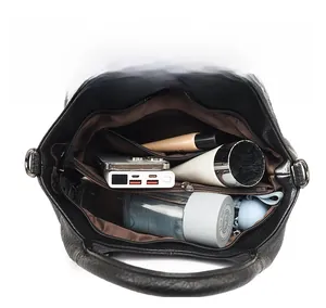 Internal view of a large black leather bag showing compartments with personal items