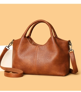Close-up of brown textured leather handbag featuring round handles and a wide shoulder strap