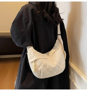 Detail of beige quilted dumpling bag showing the rhombus stitching and adjustable strap
