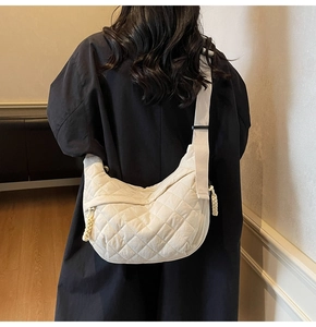 Detail view of the quilted cream hobo bag with braided zipper on a black coat model