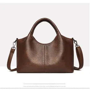 Detailed front view of dark brown textured leather tote bag with gunmetal hardware detail