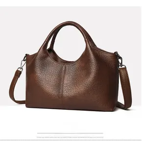 Close-up of deep brown leather tote bag showing rich lychee grain texture and handles