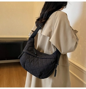 Detail of black quilted dumpling bag with adjustable strap and textured zipper pull