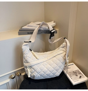 Detail of white quilted hobo bag featuring geometric stitching and wide adjustable strap