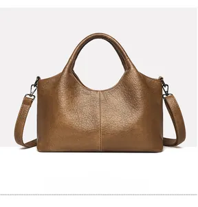 Detail of brown litchi pattern leather tote bag with sturdy handles and metallic hardware