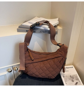 Detail of brown quilted nylon crescent bag with woven zipper pull and buckle strap
