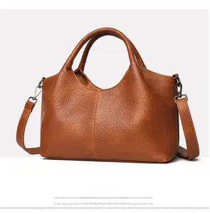 Side view of brown pebbled leather tote bag with dual handles and detachable shoulder strap