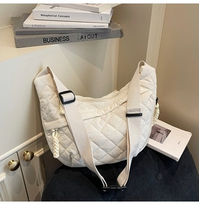 Detail of white quilted dumpling bag with adjustable strap and woven rope zipper pull