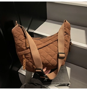 Detail of brown quilted crescent bag featuring diamond stitching and adjustable buckle strap