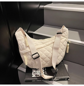 Close-up of quilted crescent bag with adjustable wide strap and woven rope zipper detail