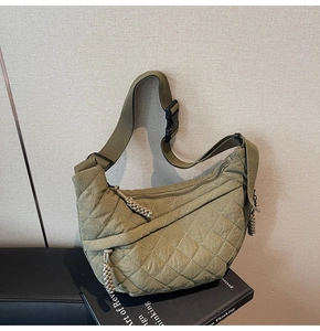 Detail of green quilted crossbody bag showing nylon texture and braided zipper pulls