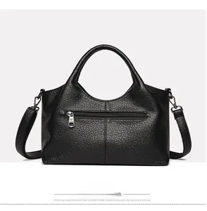 Detail view of black pebble leather tote bag back side with metal zipper pocket and strap