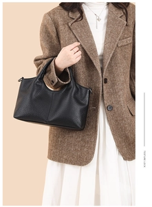 Detail of black pebbled leather handbag with curved top and textured finish